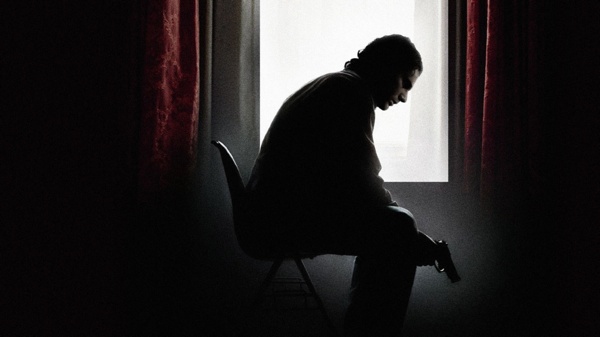 Man sits in shadows with gun