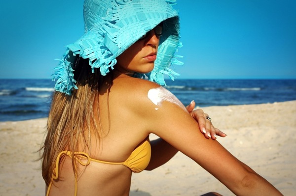 Woman Applies Sunscreen At Beach