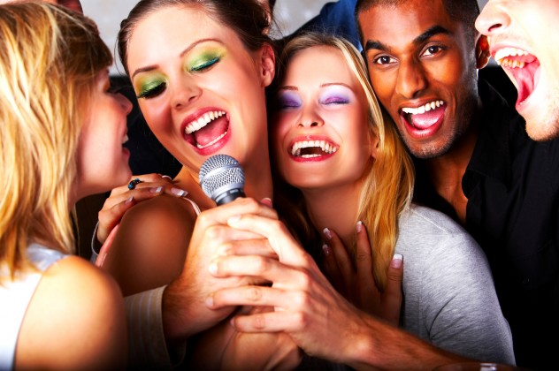 Five attractive friends singing together at a karaoke party
