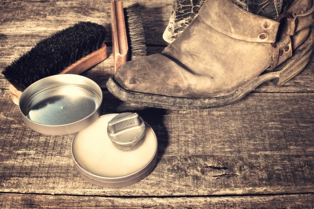 Shoe wax, boot and brushes on wooden surface