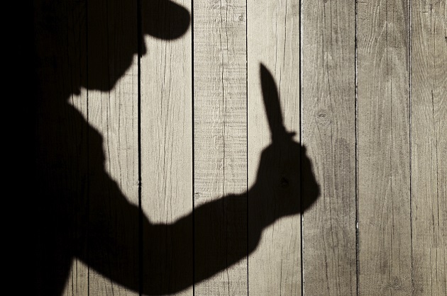 Human Silhouette with Knife in Shadow on wooden background, with space for text or image.