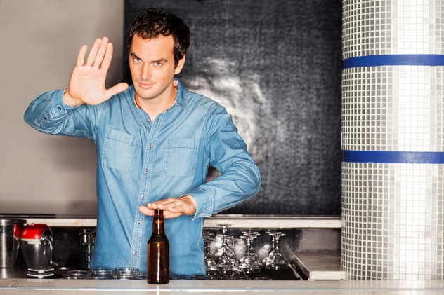Bartender With Beer Bottle Gesturing Stop Sigh At Counter